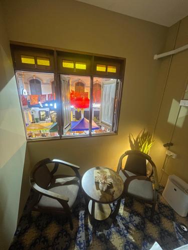 马六甲The Grand Bali Hotel的一间设有两把椅子、一张桌子和一个窗户的房间