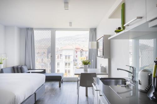沃韦沃韦公寓式酒店的厨房以及带床和水槽的起居室。