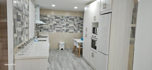 塞维利亚chalet El campillo的一间厨房,配有白色橱柜和一间餐厅