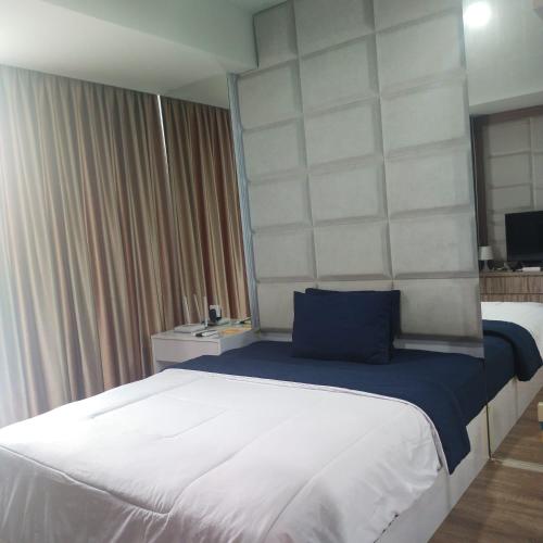 Sepinggang-besarApartemen Skylounge Balikpapan 2BR的一间卧室配有一张带蓝色枕头的大床