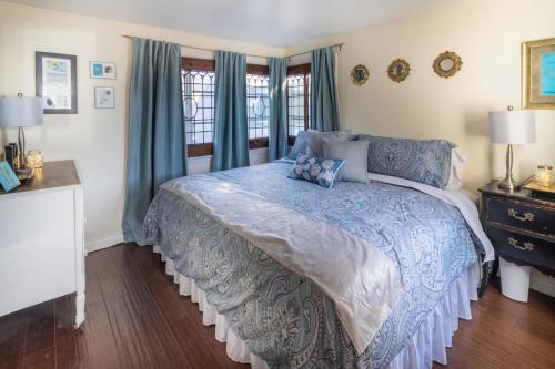 拉古纳海滩MAGICAL COTTAGE DIRECT OCEAN VIEW BEACH W GARAGE, YARD, FIREPLACE的一间卧室配有一张带蓝色棉被的床