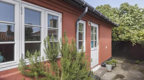 阿灵厄Rummeligt byhus i Allinge med værelse i stueplan og havkig的一间红色的房子,有白色的门和一些植物