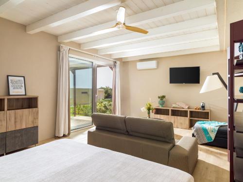 瑞塔尼Agua Green Resort的一间卧室配有一张床、一张沙发和一台电视。