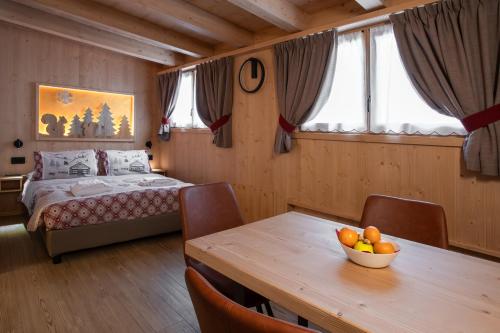 博尔米奥Chalet al Tabià的一间卧室配有一张床和一张桌子,上面放着一碗水果