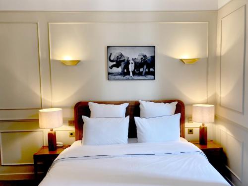 波城Hôtel Bristol Pau的一间卧室配有一张带白色床单和两盏灯的床。