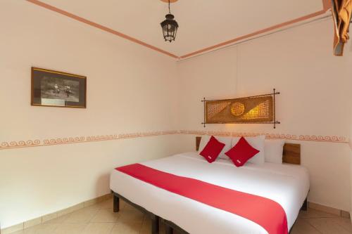 XicoOYO Hotel Coyopolan的卧室配有带红色枕头的白色床