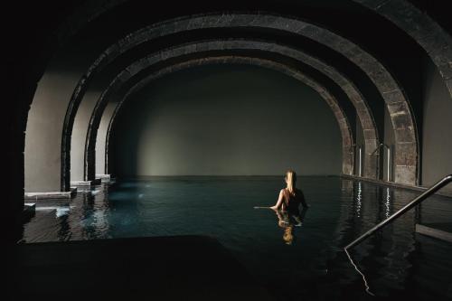 蓬塔德尔加达NINE DOTS Azorean Art Boutique Hotel的坐在隧道水中的女人