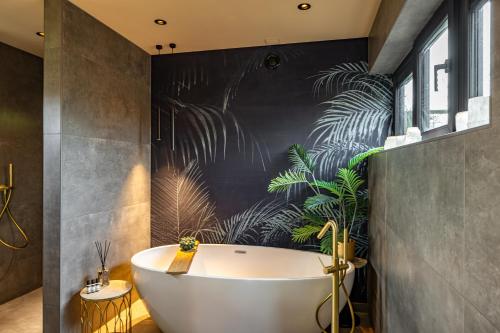 GarrelsweerLandgoed Schoolland的带浴缸和墙上植物的浴室。