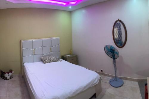 达喀尔Jumeau Lo的卧室配有白色的床和紫色灯