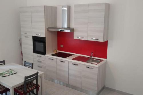 马利耶La casina di Laura的厨房配有白色橱柜和红色墙壁
