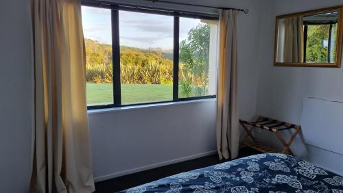 奥克兰Okura River Estate Getaway的一间卧室设有一张床和一个大窗户