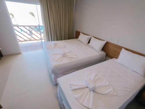 图托亚Oiti Beach Resort Tutoia的配有弓的酒店客房内的两张床