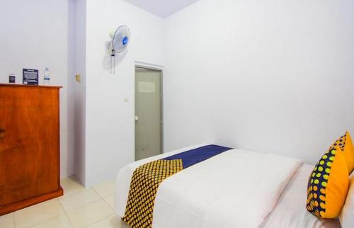 RogojampiHomestay的一间卧室配有白色的床和黄色及蓝色枕头