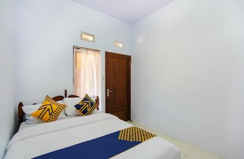RogojampiHomestay的一间卧室配有黄色和蓝色枕头的床