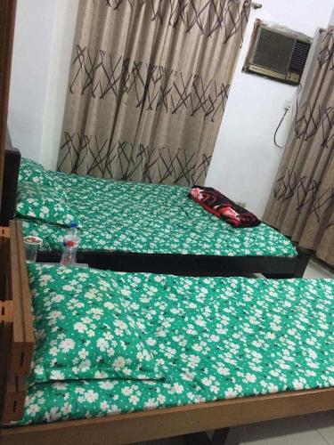 达卡Rainbow Guest House的一间卧室配有两张带绿色棉被的床