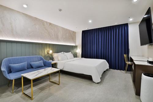 庆州Hotel Palace Gyeongju的酒店客房,配有床和蓝色的沙发