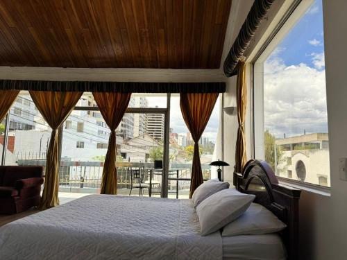 基多Suites & Hotel Gonzalez Suarez的一间卧室设有一张床和一个大窗户