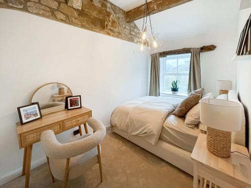 MiddlesmoorMiddle Cottage的一间卧室配有一张床、一张书桌和一面镜子
