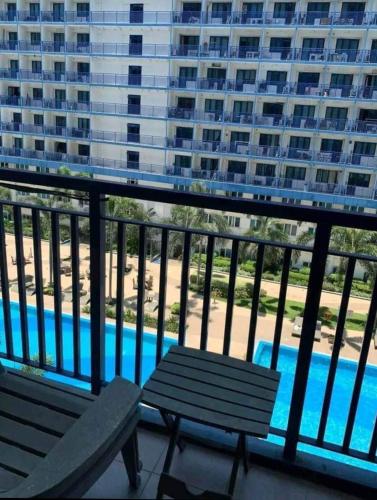 马尼拉Benedick Place at sea residences的阳台设有2张长椅,享有游泳池的景致。