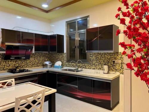 FuvahmulahSaina Dive Residence - Fuvahmulah, Maldives的厨房配有黑色橱柜、桌子和红色鲜花