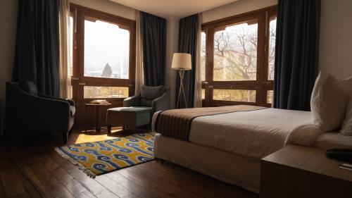 廷布不丹廷布沃瑟酒店的一间卧室配有一张床、一把椅子和窗户。