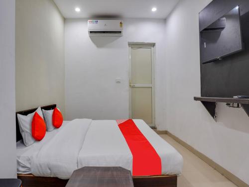 博帕尔OYO Flagship Hotel Golden Cheery的一间卧室配有一张带红色枕头的床和一台电视。