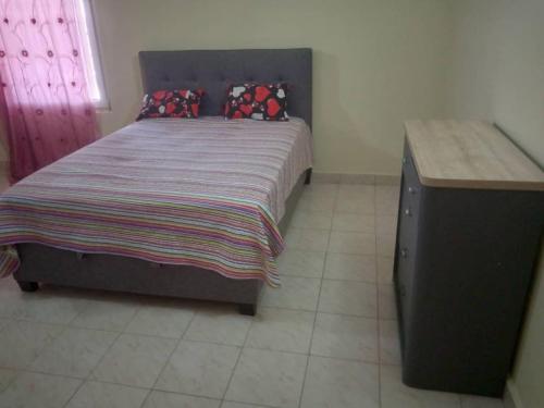 Ghana TownCostal Road hideout!的一间卧室配有一张大床和一张木桌
