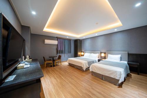 东海市I-check Hyunjin Hotel的酒店客房设有两张床和一台平面电视。