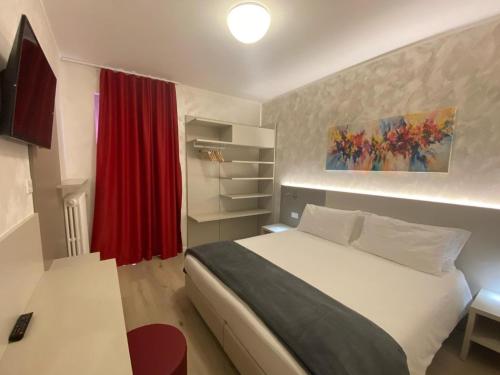 托尔博莱Hotel Angelini的卧室配有白色的床和红色窗帘