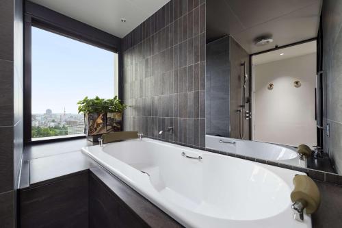 金泽Hyatt Centric Kanazawa的带浴缸的浴室和大窗户