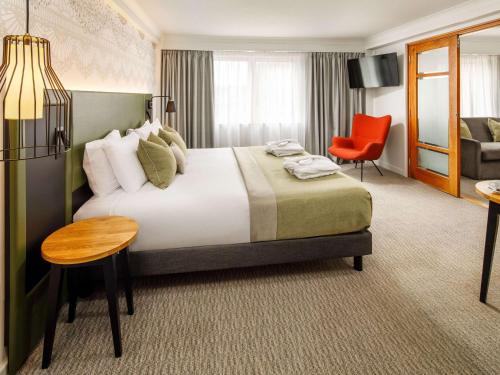 诺丁汉Mercure Nottingham Sherwood的酒店客房设有一张大床和一张红色椅子。