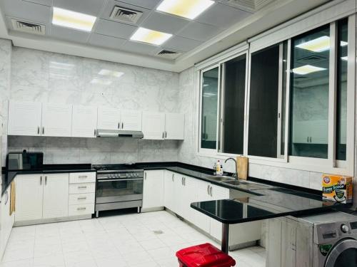 迪拜Centerpoint Duplex Villa的厨房配有白色橱柜和黑色台面