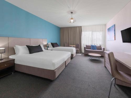 梅尔顿Mantra Melbourne Melton的酒店客房,设有两张床和一张沙发