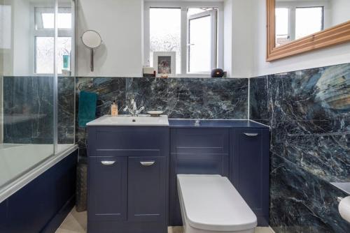 伦敦Stunning 3-Bed House的浴室配有蓝色水槽和卫生间。