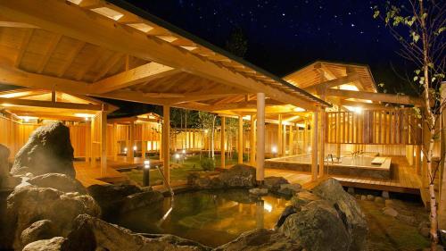 八幡平市ANA Crowne Plaza Resort Appi Kogen, an IHG Hotel的庭院内带池塘的木屋