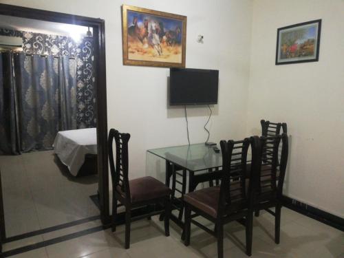 拉合尔Two Bedrooms Apartment Near DHA & Airport的配有桌椅和电视的客房