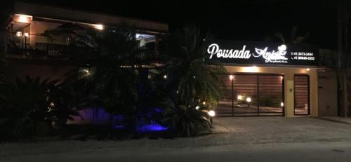 马蒂尼奥斯Pousada Anjos - à 2 quadras do mar的一间在晚上拥有棕榈树的餐厅