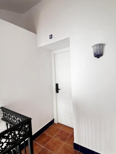 马拉加Shanti’s Andalusian Rooms的一条带白色墙壁和门的走廊