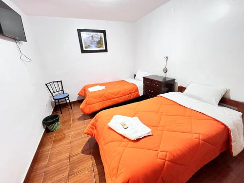 瓦拉斯Sunrise Guest House的配有橙色床单的客房内的两张床