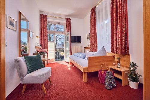 加尔米施-帕滕基兴艾森尼酒店的卧室配有床、椅子和窗户。