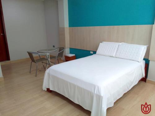 LambayequeHostal Tulipán Rojo的卧室配有白色的床和桌子