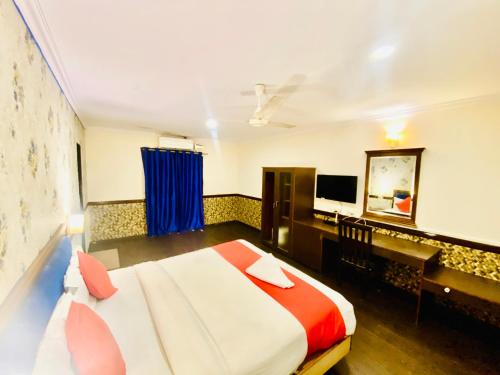 海得拉巴The City Park hotel的一间卧室配有一张床、一张书桌和一台电视