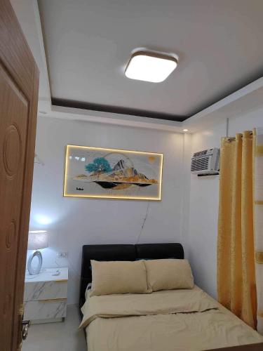 Bayugan CityJILY’s Transient Tiny House的卧室配有一张床,墙上挂有绘画作品