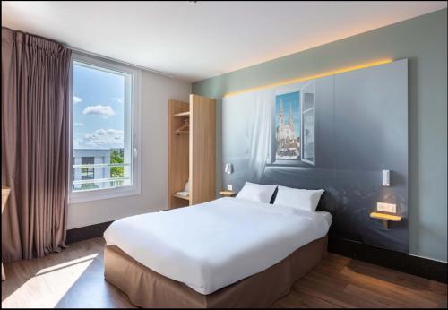 沙特尔B&B HOTEL CHARTRES Oceane的窗户客房内的一张大白色床