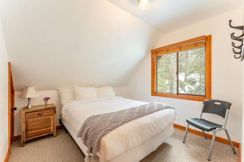 霍姆伍德Indigo Owl by AvantStay Cabin w Hot Tub Firepit Minutes to Lake Slopes的卧室配有床、椅子和窗户。