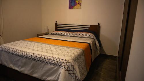 波哥大Encantador cómodo y confortable.的一间卧室配有一张带橙色和白色棉被的床