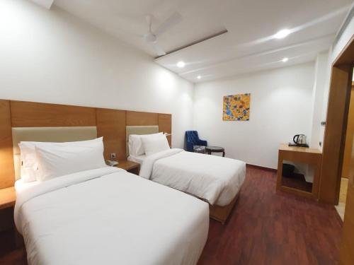 瓜廖尔The Moziac Hotel的配有白色床单的酒店客房内的两张床