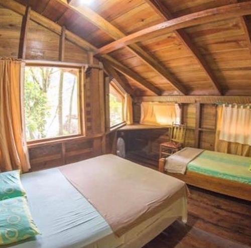 拉塞瓦Jungle River Lodge的木制客房内的一间卧室配有两张床