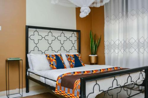 坎帕拉Naalya Motel的一间卧室配有一张带橙色和白色棉被的床