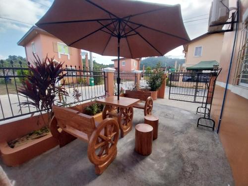 苏比克Cozy Corner at Camella Subic Vista Estates的天井配有桌子、长凳和遮阳伞。